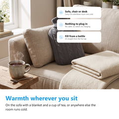 Hot water bottle with knitted cover resting on a sofa with a throw blanket