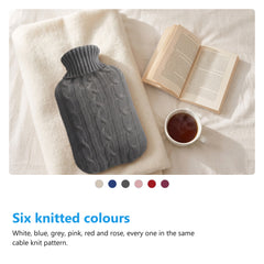 Hot water bottle with knitted cover on a bed with a book and tea, with the six colours below it