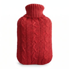 Hot water bottle with a red knitted cable cover on a white background