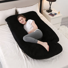 Charcoal black J shaped pregnancy pillow on a bed with a woman resting inside it