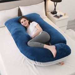 Navy and light grey J shaped pregnancy pillow on a bed with a woman resting inside it