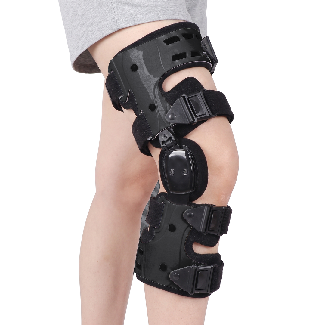 The same hinged knee brace in black, worn on a leg on a pure white background, with two rigid shells, a side hinge and four quick release straps