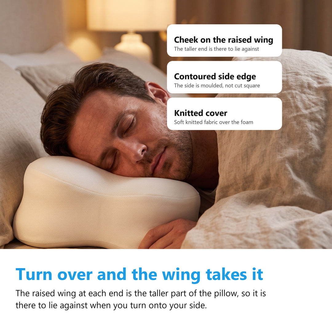 Man asleep on his side with his cheek against the raised end wing of the contoured memory foam pillow