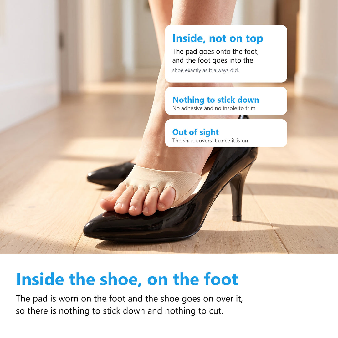 Foot wearing a nude metatarsal pad stepping into a black patent court shoe on a wooden floor