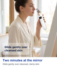 Two minutes at the mirror: gliding the pore vacuum device gently over cleansed, damp skin, woman wearing a robe