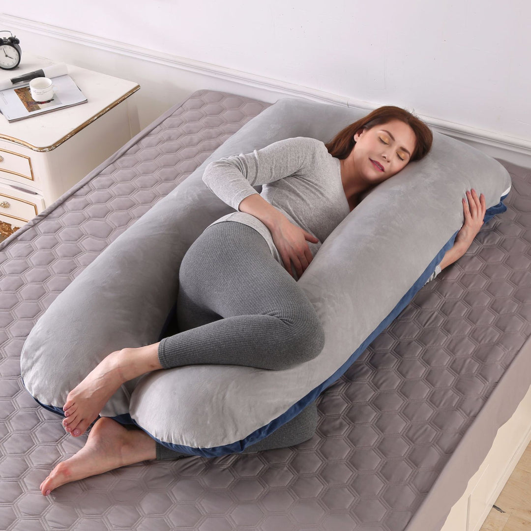 U shaped pregnancy pillow in navy and grey velvet laid out on a bed