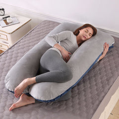 U shaped pregnancy pillow in navy and grey velvet laid out on a bed