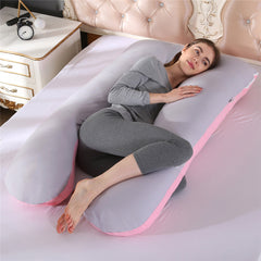 U shaped pregnancy pillow in pink and grey cotton laid out on a bed