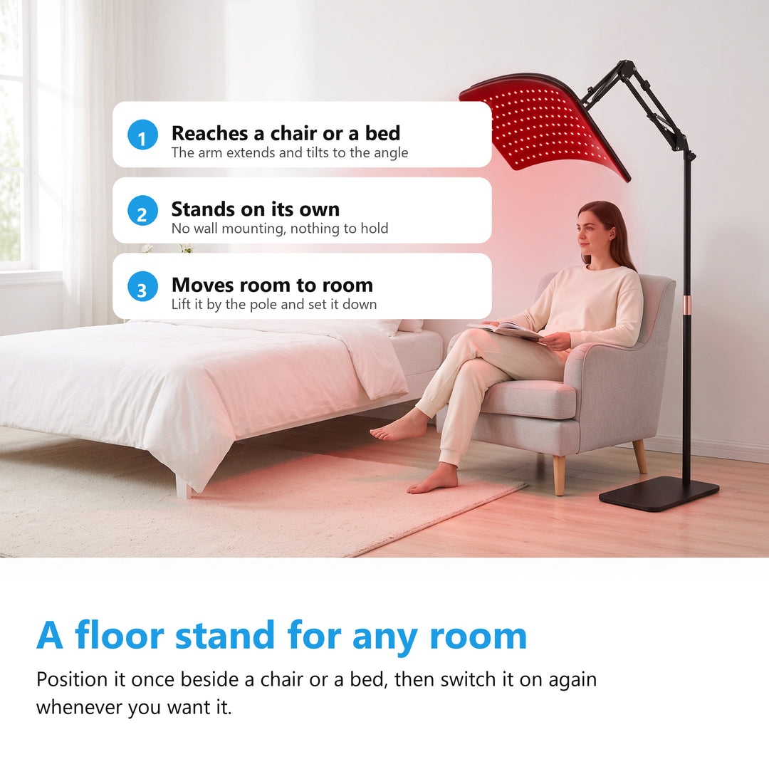 Woman sitting in an armchair in a white bedroom beside a red light therapy lamp on its floor stand