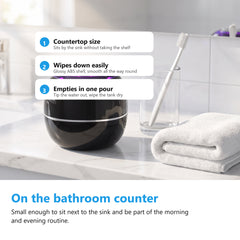 Ultrasonic denture cleaner on a bathroom countertop beside a toothbrush glass and a folded towel