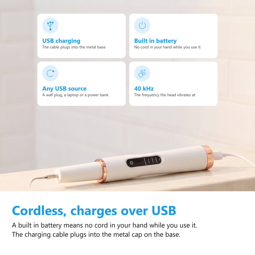 Ultrasonic tooth cleaner charging over USB, the cable plugged into the metal base on the handle