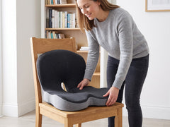 Memory foam seat cushion with back support being placed on a wooden chair