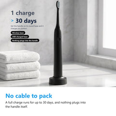 Black electric toothbrush on its wireless charging base on a bathroom counter