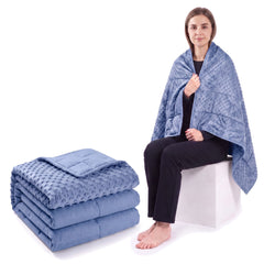 Royal blue weighted blanket folded on a white background beside a woman wrapped in the same blanket