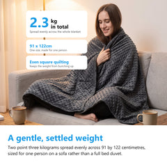 Woman on a sofa wrapped in a 2.3kg weighted blanket measuring 91 by 122cm