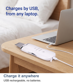 Ultrasonic skin scrubber charging by USB cable beside a bed